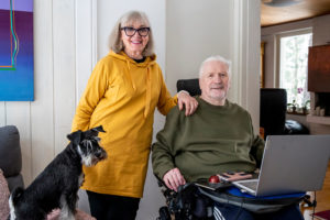 Eija-Maaria Jussila ja pyörätuolissa istuva Reijo Ahteela koiran kanssa.