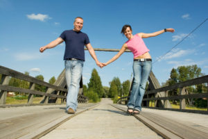 Pariskunta ylittää siltaa pitäen toisiaan kädestä kiinni, mutta nojautuen pois päin toisistaan.